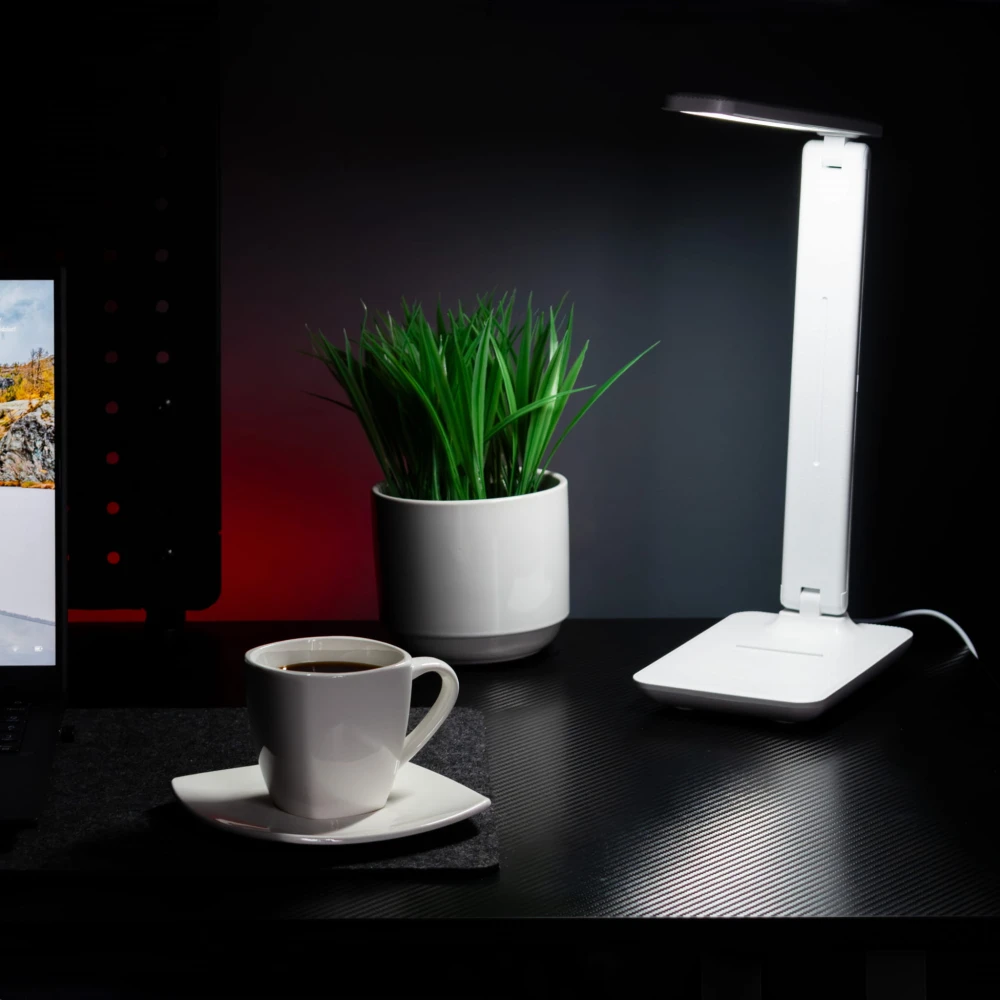 Lampka Post na biurku obok laptopa, filiżanki i rośliny